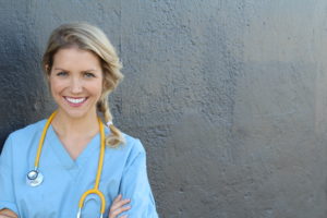 Junge lächelnde Ärztin mit blauen Kittel und Stethoskop